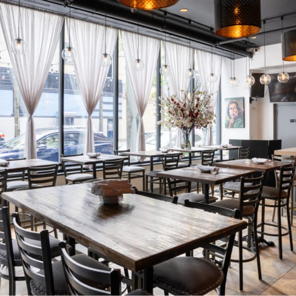 Interior of Krave restaurant with wooden tables, black chairs, large windows, and hanging lights.