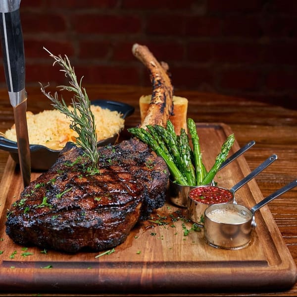 Grilled steak with rosemary, asparagus, and sauces on a wooden board at Krave.