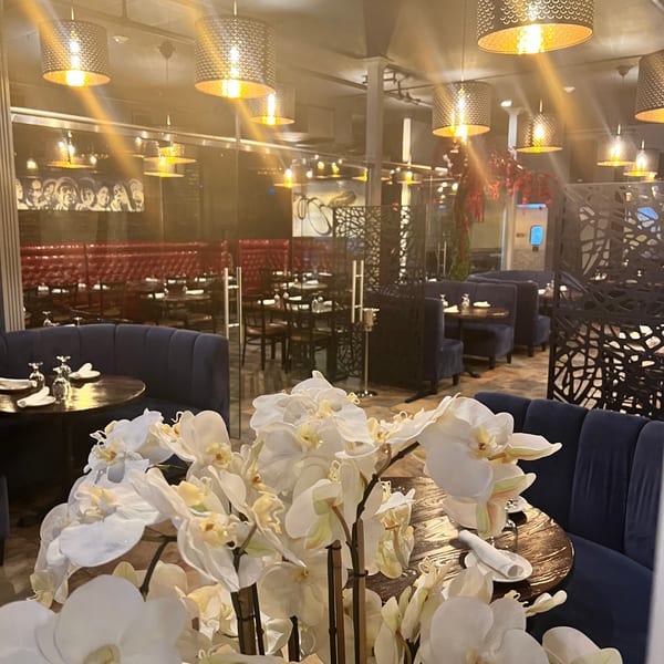 Elegant Krave restaurant interior with white orchids, blue booths, red banquettes, and decorative lighting.